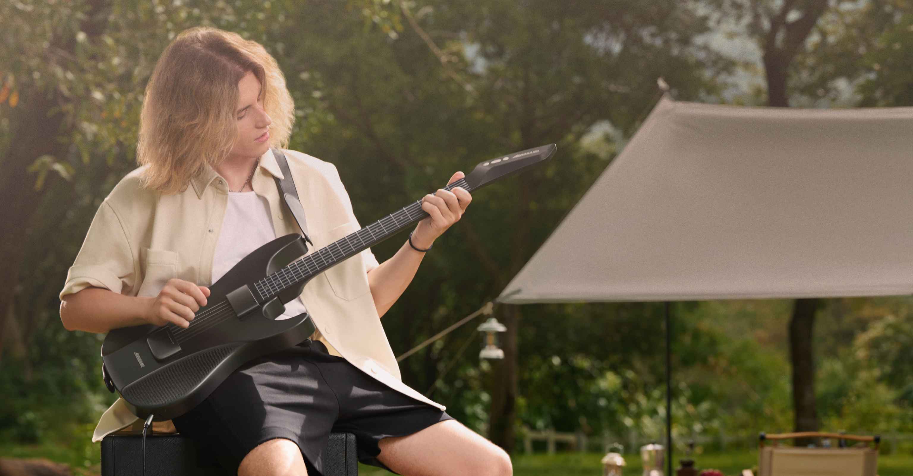 A man plays Aeroband Guitar while camping